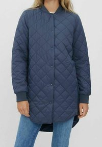 Marinblå vadderad lång kappa med rund krage, knappstängning och ribbade ärmmuddar; med diamantmönster och förlängd bakslut. 