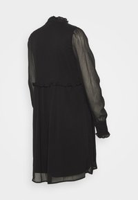 Vestido preto com mangas longas transparentes, detalhes em babados no pescoço e na cintura, e uma silhueta fluida com uma bainha que termina a meio da panturrilha.