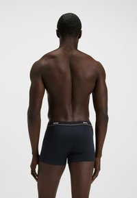 Black boxer briefs with a fitted design, featuring a contrasting waistband with "BOSS" logo and smooth fabric texture.