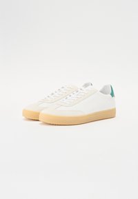 White sneakers with a smooth leather upper, beige rubber sole, and teal accent at the heel. Features flat white laces and rounded toe.
