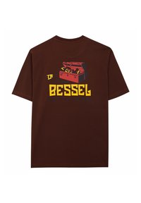 Camiseta de algodón marrón con un gráfico de una caja de herramientas, la palabra "BESSEL" y la frase "A TRABAJAR" en letras amarillas y azules.