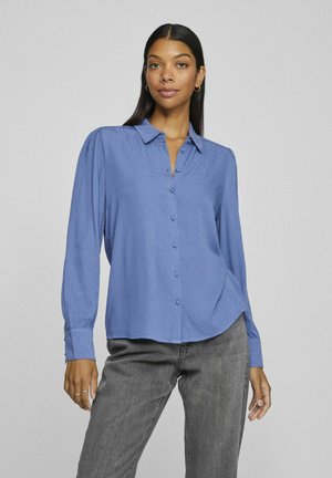 Lichtblauw blouse met een knoopsluiting aan de voorkant, lange mouwen en een gestructureerd patroon. Zachte stof, flatterende pasvorm en een kraagdetail.