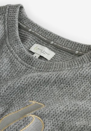 Grauer gestrickter Pullover mit strukturiertem Muster, rundem Halsausschnitt und goldenen Akzenten. Das Etikett lautet "Ted Baker London."