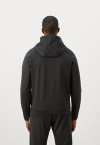 Svart hettegenser med en glatt tekstur, ribbede mansjetter og hem. Den har en tett passform og et enkelt, minimalistisk design.