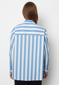 Camicia con colletto in azzurro chiaro e righe verticali bianche, con maniche lunghe e polsini a bottoni, caratterizzata da una vestibilità ampia e dettaglio sul retro con yoke.