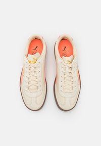 Baskets en cuir beige avec des accents roses, des côtés texturés et des lacets crème. Dotées d'un logo doré sur la languette et d'un intérieur rembourré.