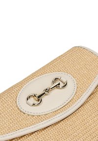 Borsa in paglia intrecciata con una patta in pelle beige chiaro. Presenta una chiusura in metallo di colore argento e un dettaglio ovale decorativo. Texture liscia.