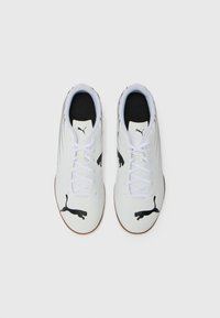Hvite sportsko med svarte Puma-logoer, med en glatt syntetisk overdel, snøringsdesign og gummisåle.