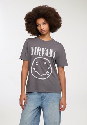 T-shirt grigio in cotone con una grande scritta bianca "NIRVANA" e una grafica di faccina sorridente con gli occhi incrociati. Vestibilità morbida con maniche corte.