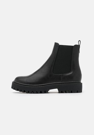 Sort Chelsea-støvle i læder med elastisk sidepanel, trækklap ved hælen og kraftig mønstret sål, vist i profil på hvid baggrund.