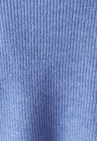 Tissu tricoté de couleur bleu clair avec une texture côtelée verticale. Matériau doux avec une couture régulière et des variations subtiles de couleur sur l'ensemble.