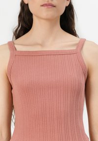 Ribbed tank top in dusty rose, featuring thin shoulder straps and a square neckline. Smooth texture with subtle vertical lines.