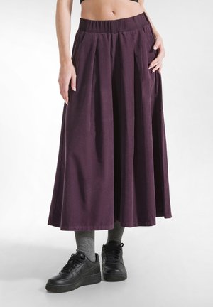 Lange, paarse katoenen rok met geplooid ontwerp, gathered tailleband en zakken, gecombineerd met zwarte sneakers en grijze sokken.