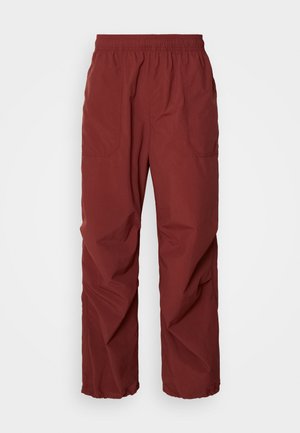Pantalones ligeros rojos con cintura elástica, dos bolsillos laterales, piernas anchas y una textura suave. Ideales para uso casual o activo.