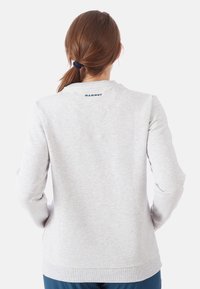 Sudadera gris de manga larga, textura suave, material ligeramente elástico, escote redondeado y logo "MAMMUT" en azul marino en la parte de atrás.
