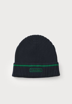 Beanie a coste di colore blu navy con un accento a righe verdi e una toppa con il marchio Calvin Klein sul risvolto. Materiale in maglia morbido.