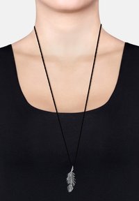Sølvfjer-vedhæng på en sort snorhalskæde, præsenteret mod en sort top. Vedhænget har detaljerede bladdesign og en poleret finish.