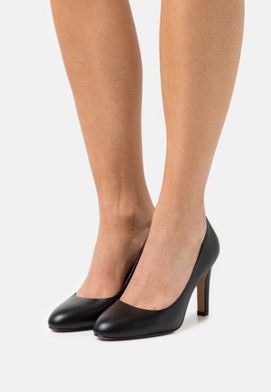 Escarpins en cuir noir avec un bout arrondi, un décolleté bas et un talon aiguille fin. Texture lisse avec un minimum de détails.