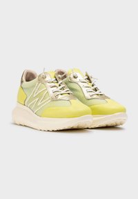 Zapatillas deportivas con parte superior de malla en amarillo claro y verde, con acentos metálicos en dorado, puntera redondeada y suela blanca gruesa.