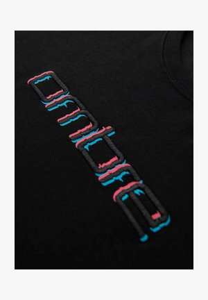 T-shirt noir avec un texte brodé en rose et bleu. Le texte présente un design moderne et angulaire avec une texture tactile. Encolure ronde.