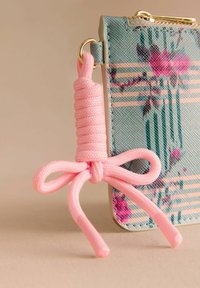 Piniginė su gėlių raštu, šviesiai mėlynos spalvos, tekstūruotu paviršiumi ir rožiniu užtrauktuko kilpeliu, primenančiu lanką. Aukso spalvos detalės.