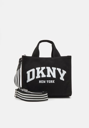 Black canvas handbag with white "DKNY NEW YORK" logo. Features dual carry handles and a detachable striped shoulder strap. Rectangular shape.