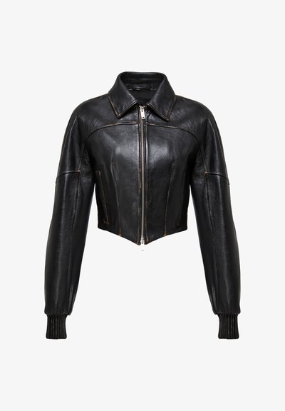 Chaqueta de piel negra corta con cuello puntiagudo, cierre de cremallera y puños acanalados. Presenta costuras visibles para un detalle y textura adicionales.