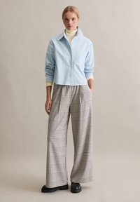 helehall sinine nööpidega särk rinnataskuga, kombineeritud laia ruudulise püksiga beeži, halli ja pruuniga. Tekstuuriga kangas ja lõdvestunud lõige.