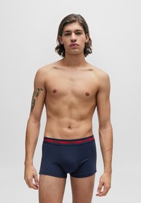 Mørkeblå bomulls boxershorts med en tettsittende design, med en rød merket midjebånd. Stoffet ser glatt og elastisk ut.