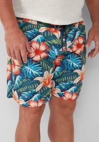 Tropische zwembroek met een multikleurig bloemmotief met grote hibiscusbloemen en bladeren. Gemaakt van lichtgewicht stof met een elastische tailleband.