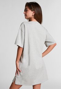 Graues, übergroßes Kurzarmkleid aus weichem Stoff, mit seitlichen Schlitzen und einem runden Ausschnitt für Komfort und Bewegungsfreiheit.
