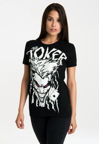 Black cotton t-shirt featuring a large graphic of the Joker with white and pink details, and an illustrated playing card.
