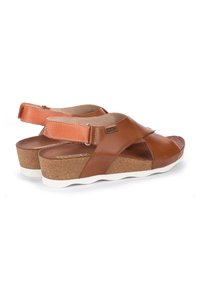 Sandali in pelle marrone con design a lacci incrociati, soletta in sughero, suola in gomma bianca e cinturino alla caviglia regolabile per una vestibilità sicura.
