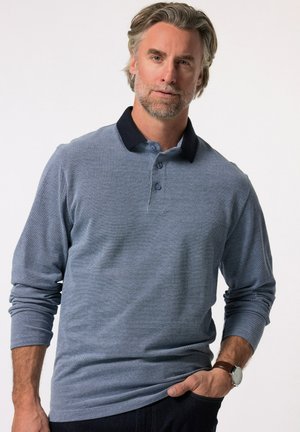 Polo de manga larga en azul claro con cuello marino, con tres botones en la parte delantera y tejido texturizado. Combinado con jeans oscuros y un reloj.
