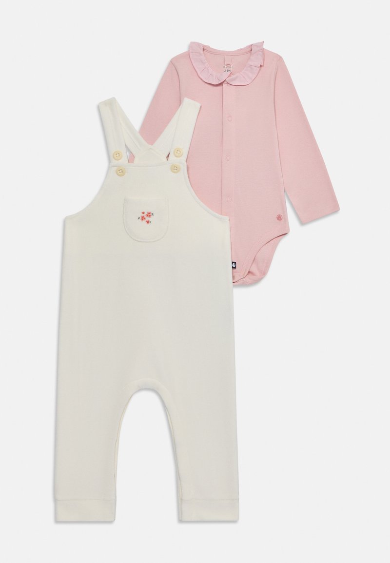 Cremfarbene Baby-Overalls mit floralem Taschenstickerei, kombiniert mit einem pinken Langarm-Body mit Rüschenausschnitt und Frontknöpfen.