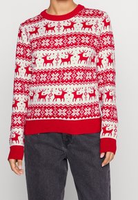 Roter und weißer Pullover mit Rentier- und Schneeflockenmuster, Rundhalsausschnitt, gerippte Bündchen und Saum, aus Strickstoff gefertigt.