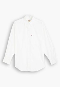 Chemise blanche à manches longues avec un col boutonné, arborant un petit logo rouge sur la poitrine gauche et un ourlet arrondi. Fabriquée en tissu de coton lisse.