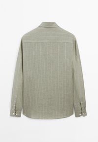 Camicia a maniche lunghe di colore verde oliva, con strisce bianche verticali, colletto e polsini con bottone. Tessuto morbido con una vestibilità rilassata.