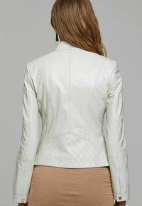 Witte leren jas met gestructureerde naden, een getailleerd ontwerp en een textuurpaneel aan de achterkant met een ruitpatroon. Lange mouwen en knoopaccenten.
