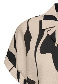 Beige shirt with black abstract pattern, featuring a notched collar and short sleeves. Textured fabric adds depth to the design.