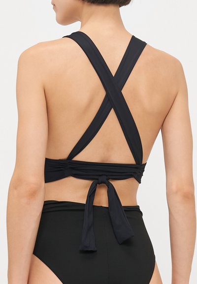 Melns bikini tops ar krustveida dizainu, regulējamu sasienamu aizmugurē, gludu tekstūru un minimālistisku stilu.