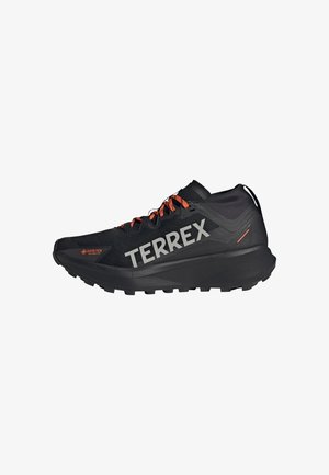 Schwarzer Trailrunning-Schuh mit GORE-TEX-Obermaterial, orangefarbenen Akzenten, prominenter TERREX-Branding, strukturiertem Profil und einem eleganten, leichten Design.