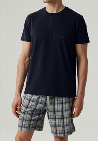 Granatowy T-shirt z krótkim rękawem z trzema guzikami i logo na klatce piersiowej, w połączeniu z szortami w kratę w odcieniach szaro-niebieskich, z elastycznym sznurkiem.