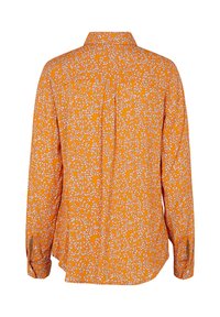 Pomarańczowa koszula z białymi kwiatowymi wzorami, z długimi rękawami, z zapięciem na guziki oraz zakrzywionym dołem. Z tyłu znajduje się plisowanie dla wygody ruchu.