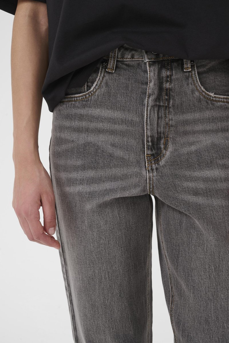 Jean en denim gris à coupe légèrement ample, avec effets d'usure visibles, surpiqûres contrastantes et fermeture à boutons.