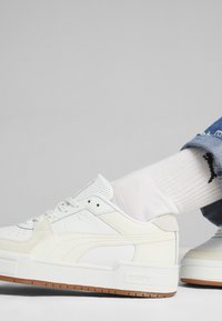 Vita sneakers i läder med texturerade detaljer, snörningsdesign och en sula i gummi. Har perforerade detaljer och varumärkeslogotyp på sidan.