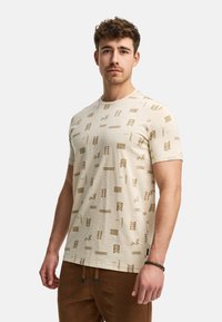Beige T-Shirt mit kurzen Ärmeln und texturierter Oberfläche, die abstrakte geometrische Muster in Braun zeigt. Rundhalsausschnitt und lockere Passform.