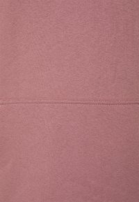 Soft, textured fabric in muted pink, featuring a stitched seam across the middle, with a smooth finish and uniform color.