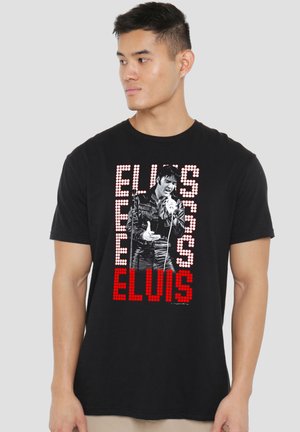 Man wearing black t-shirt with black-and-white Elvis Presley singing image and "ELVIS" text in red and white dots.