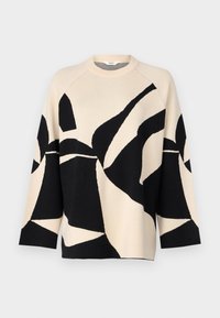 Pull-over en tricot avec une base beige ornée de motifs abstraits noirs, un col rond et des manches raglan longues. Tissu doux et texturé.